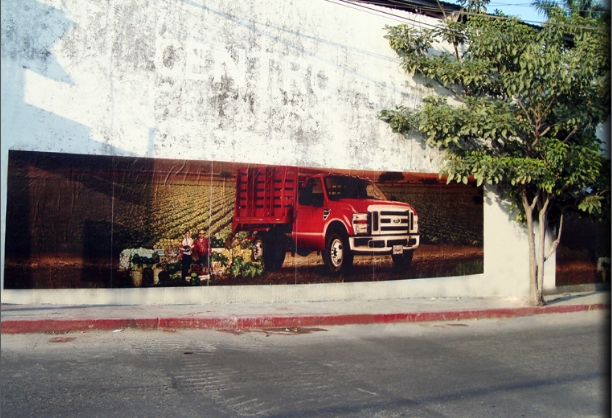 Publicidad en barda con una camioneta roja.
